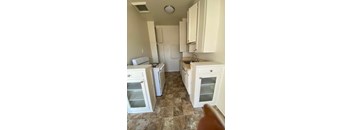 A kitchen with white cabinets and a tiled floor.