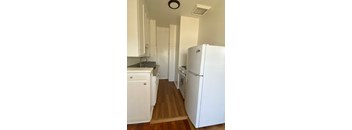 A white refrigerator is in a kitchen with white cabinets.