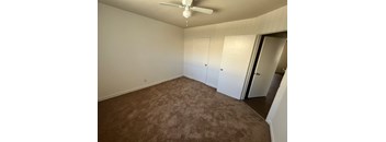 A room with a ceiling fan and carpeted floor.