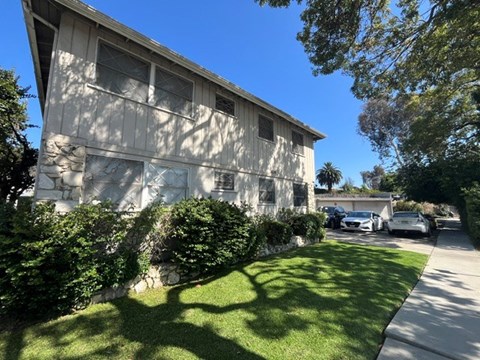 A house with a white stone wall and a green lawn.