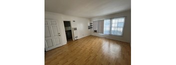 A room with wooden flooring and a window with blinds.