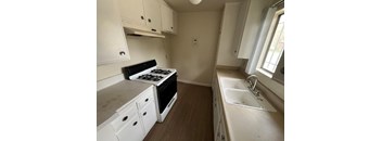 A small kitchen with a stove, sink, and cabinets.