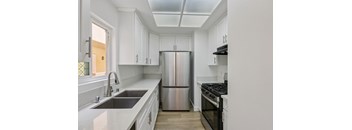 A modern kitchen with white cabinets and stainless steel appliances.