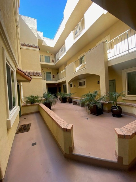 A courtyard with a tiled floor and a few potted plants.