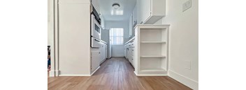 A kitchen with white cabinets and a wooden floor.