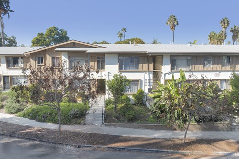 Apartment complex with trees and bushes in front.