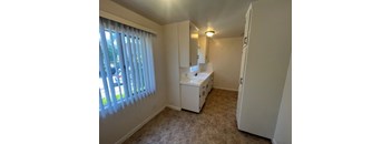 A small white bathroom with a sink and a window with blinds.