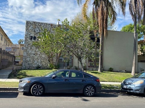 A silver car is parked on the side of a street.