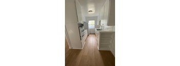 A kitchen with white appliances and wooden floors.