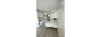 A kitchen with white appliances and cabinets.