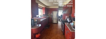 A kitchen with red cabinets and a wooden floor.