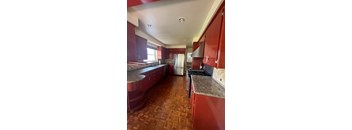 A kitchen with red cabinets and a tile floor.