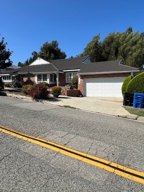 A house with a white garage door and a blue trash bin outside.