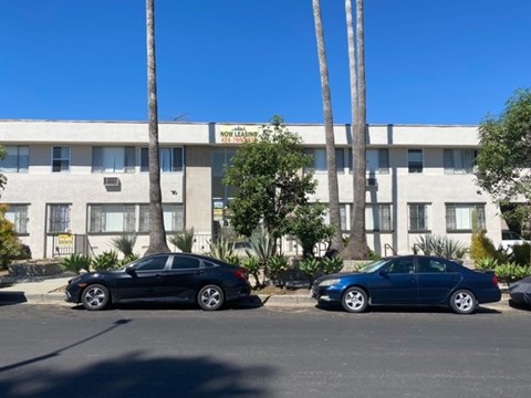 Two cars parked in front of a building with a sign that says "Now Legging".