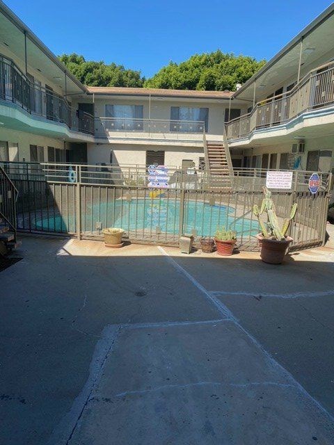 A pool surrounded by a fence and a building in the background.