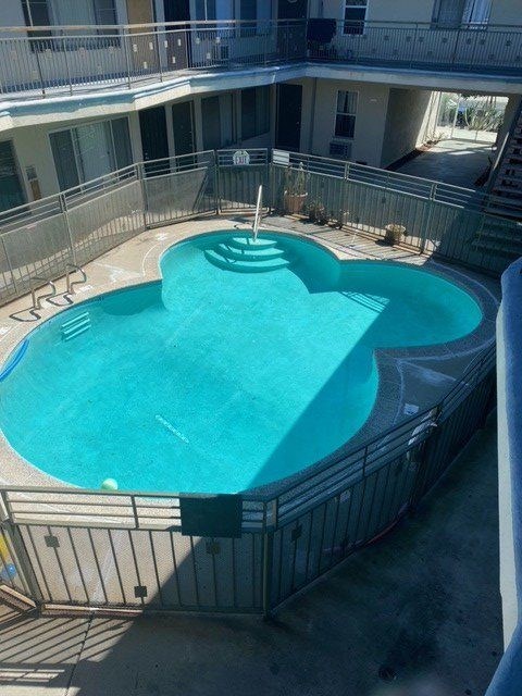 A heart-shaped pool in a courtyard surrounded by a metal fence.