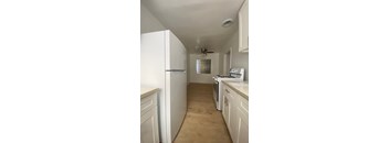 A kitchen with white appliances and cabinets.