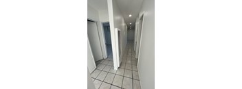 A long hallway with white walls and tile flooring.