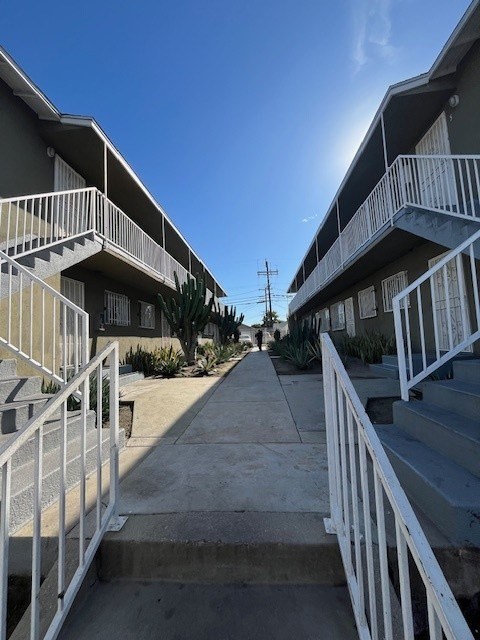 A row of apartment buildings with white railings and steps leading to the doors.