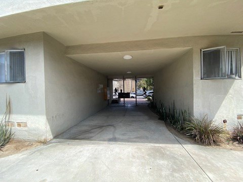 A concrete covered driveway leads to a house.
