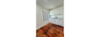 A kitchen with white cabinets and a wooden floor.