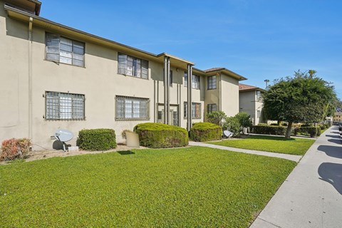 A row of apartment buildings with green lawns in front.