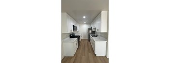 A kitchen with white cabinets and a wooden floor.