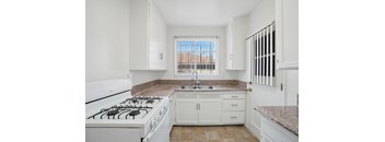 A kitchen with white cabinets and a granite countertop.