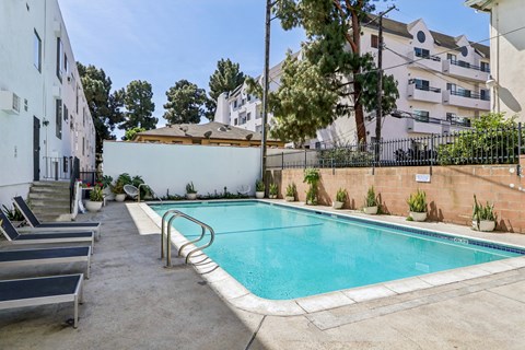 A small pool surrounded by a concrete floor and a metal fence.