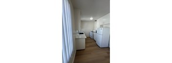 A kitchen with white appliances and wooden floors.