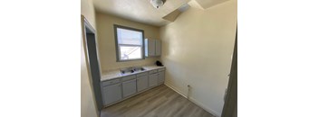 A kitchen with a window, sink, and cabinets.