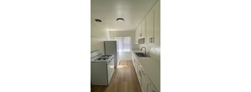 A white kitchen with a stove, sink, and cabinets.