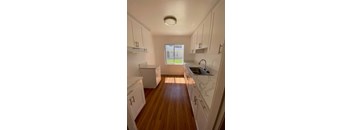 A kitchen with white cabinets and a wooden floor.