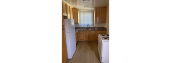 A kitchen with wooden cabinets and a white fridge.