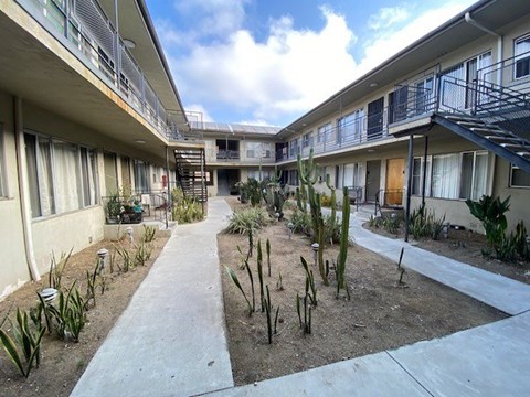 A courtyard with a concrete floor and a variety of plants and cacti.