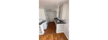 A kitchen with white appliances and wooden floors.