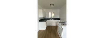 A kitchen with white cabinets and a black countertop.
