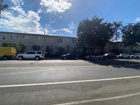 A parking lot with cars and a yellow truck in front of a building.
