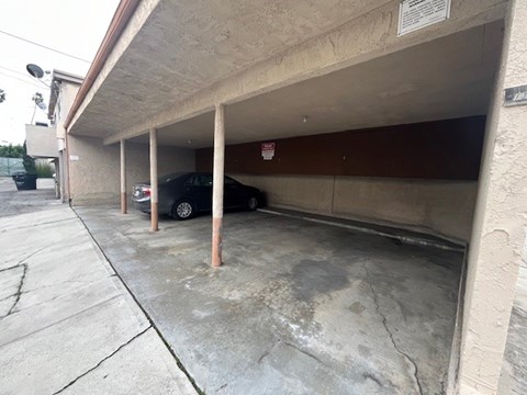 A car is parked in a garage under a no parking sign.