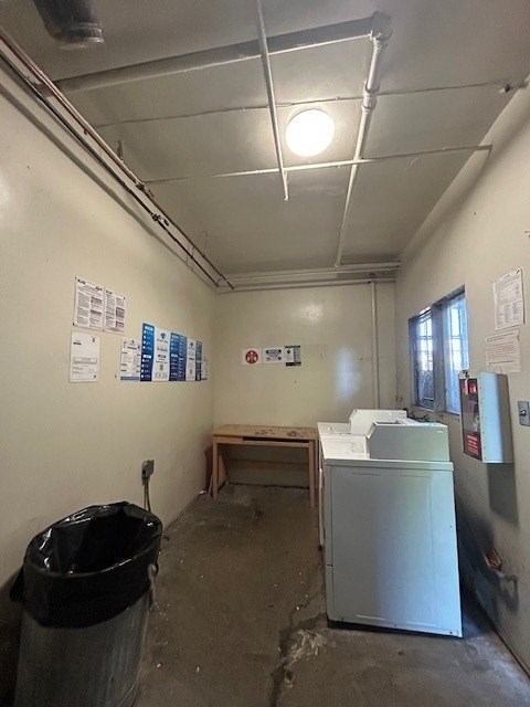 A room with a white wall and a black trash can.