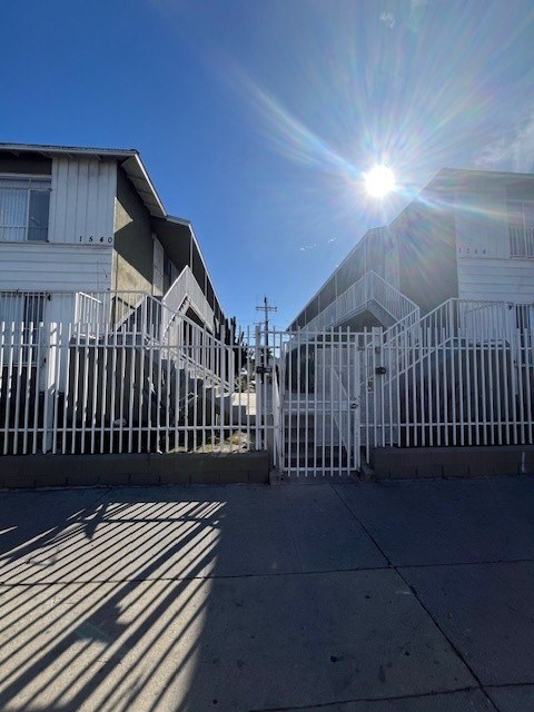 A sunny day in front of a row of houses with a bright sun in the sky.
