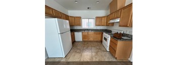 A kitchen with white appliances and wooden cabinets.