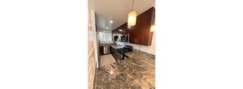 A kitchen with granite countertops and wooden cabinets.