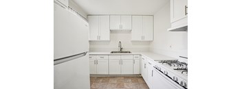 A kitchen with white cabinets and a white stove.
