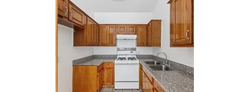 A kitchen with a white stove and wooden cabinets.