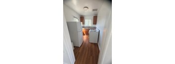 A kitchen with white appliances and wooden floors.