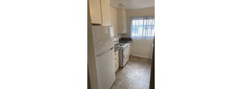 A kitchen with a white refrigerator and a black stove top.