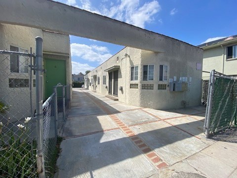A long concrete walkway leads to a green door.