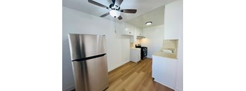 A kitchen with a stainless steel refrigerator and wooden floors.