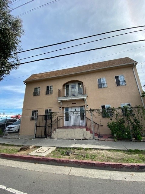 A beige house with a black gate and a red brick sidewalk.